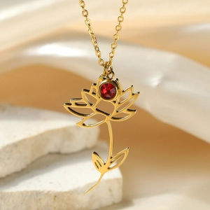 Macro shot of 18k gold plated lotus flower pendant with red crystal birthstone detail