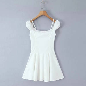White mini dress with lace trim and puff sleeves hanging on a wooden hanger