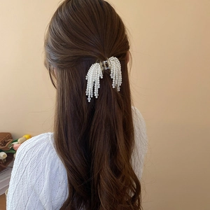 Detailed view of elegant artificial pearl tassel hair claw clip worn in a half-up hairstyle