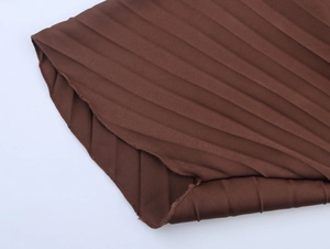 Detailed macro view of the pleated brown fabric texture and edge stitching on the dress