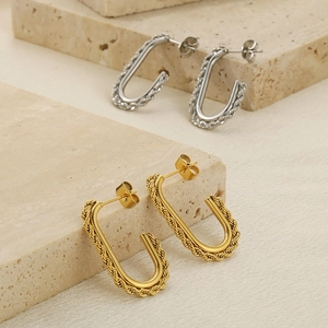 Detailed macro of gold and silver U-shaped twist earrings on a natural stone base