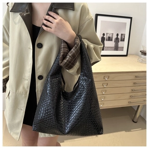 Close-up of black woven leather hobo bag showing texture and slouchy design on a model