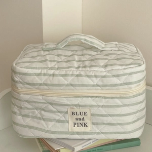 Quilted cotton makeup bag with green stripes and handle on aesthetic book stack