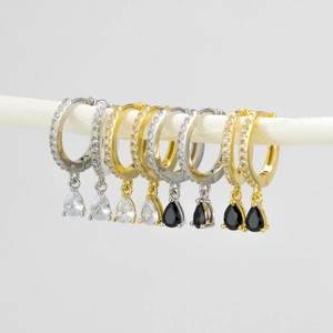 Detailed macro view of S925 silver needle drop earrings with diamonds in gold and silver