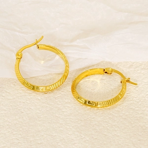 Macro detail of 18K gold-plated titanium earrings featuring classic Greek key patterns
