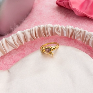 Close-up of pink heart zircon ring with star details on a soft silk eye mask