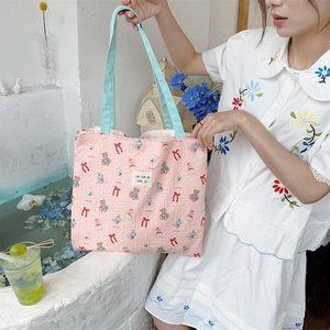 Close-up of pink quilted canvas tote bag with cartoon bear patterns and blue straps