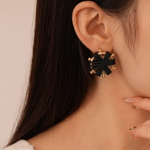 Detail view of round woven faux leather earrings with golden base on a female model