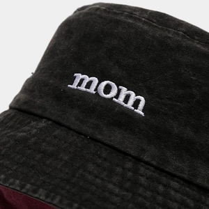 Detail of mom embroidery on washed black cotton bucket hat with dark red lining