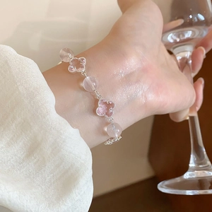 Close-up of pink four-leaf clover beaded bracelet with clear beads on a woman's wrist