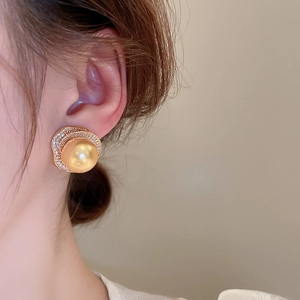 Vue rapprochée d'une boucle d'oreille perle dorée avec double rangée de cristaux fins