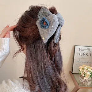 Elegant grey knitted hair claw clip with blue crochet flowers shown on hair