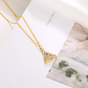 Macro view of gold triangle pendant necklace with clear cubic zirconia and textured finish