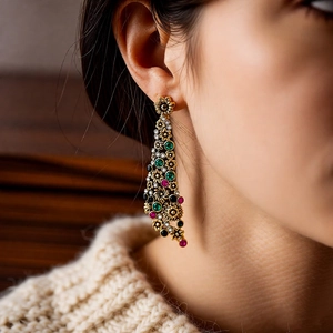Primo piano di orecchini vintage a fiore dorati con cristalli colorati su modella