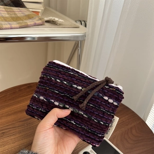 Detailed knit texture of burgundy striped mini coin purse with a simple wish label