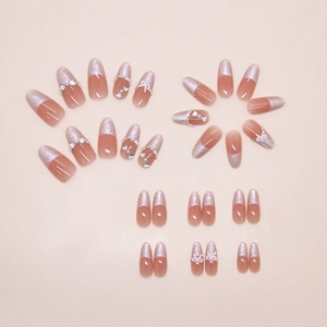 Detail of French press-on nails with 3D pink bows, pearls, and sparkling rhinestones