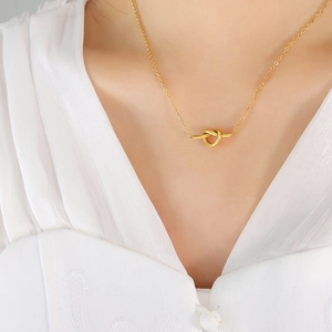 Elegante gouden knoop hanger ketting van titanium staal op model met V-hals top