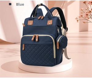 Close-up of blue quilted diaper bag with brown leather accents on a stylish background