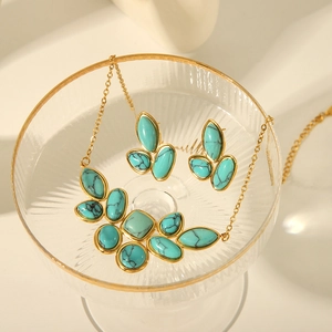 Detail of turquoise stone jewelry set with gold necklace and earrings in a glass