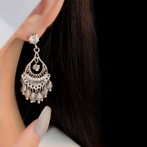 Vue détaillée de boucles d'oreilles argentées en gouttes d'eau avec glands sur mannequin