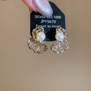 Detailed close-up of gold hollow petal pearl earring with silver needle and zircon accents