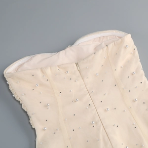 Dettaglio dell'abito in rete color crema con perle cucite a mano e zip invisibile