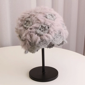 Close-up of handmade crochet winter beanie with 3D floral details and soft faux fur texture