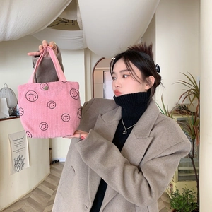 Detail of pink corduroy tote bag with black smile prints and metallic snap closure