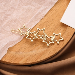 Golden alloy hair clip featuring five hollow star shapes on a wooden display tray