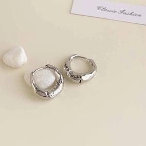 Detailed macro view of silver hammered texture hoop earrings on a minimalist background