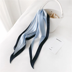 Blue and white striped silk scarf tied as a decorative accessory on a white leather handbag