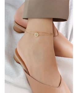 Detail of 18k gold double-layer ankle chain with hollow round charm on model