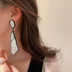 Irregular geometric acrylic earrings with marble pattern and black trim on model