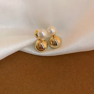 Elegant gold plated pearl earrings on silk background featuring a minimalist round design