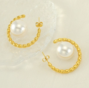 Macro shot of 18k gold plated C-shape earrings with beaded texture and large white pearls