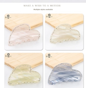 Macro view of heart-shaped hair clips with marble texture and rhinestones in four colors