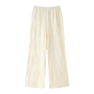 Détail d'un pantalon large blanc crème avec broderie florale complexe et texture douce