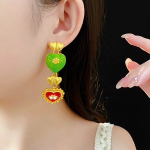 Detail of vintage heart earrings with green and red enamel and pearls on model