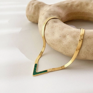 Elegant 18K gold-plated V-shaped necklace with green malachite inlay on a minimalist stand