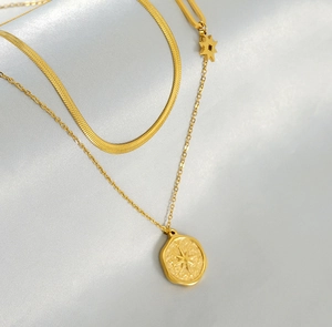 Detail of gold double-layered necklace with hexagram coin pendant on grey silk