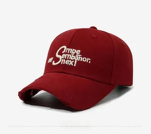 Detailed side view of washed burgundy baseball cap featuring white 3D embroidery and distressed brim