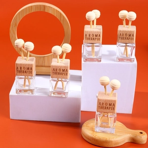 Close-up of five square glass car perfume bottles with engraved wood caps and reeds