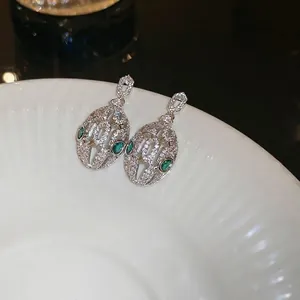 Luxurious silver snake-shaped hollow earrings with green stones and sparkling cubic zirconia
