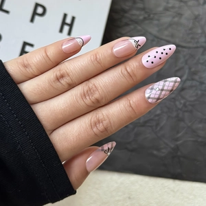 Detail von Mandel-Press-on-Nägeln mit rosa Gittermuster, schwarzen Punkten und Spitzen-Design