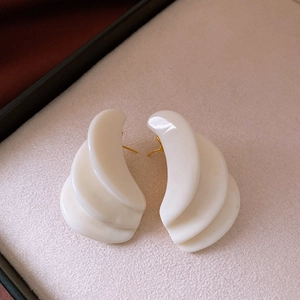 Detailed macro view of cream resin layered geometric earrings with gold stud backing