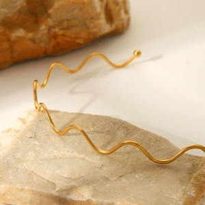 Elegant 18K gold-plated stainless steel wavy necklace displayed on aesthetic stone props