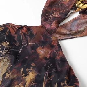 Detail of abstract print mesh fabric featuring a gold metal buckle on the neckline