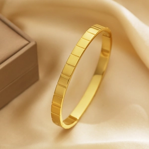 Dettaglio del motivo a griglia dorata e della trama lucida sul bracciale in acciaio inox