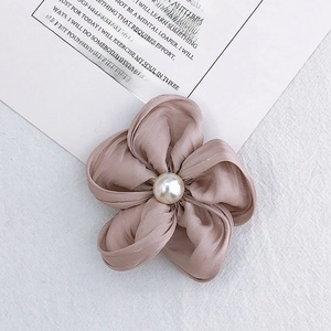 Close-up of handmade satin flower hair accessory with central white pearl in dusty pink