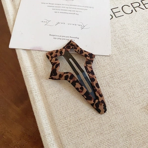 Dettaglio del fermaglio per capelli a stella con stampa leopardata su sfondo vintage